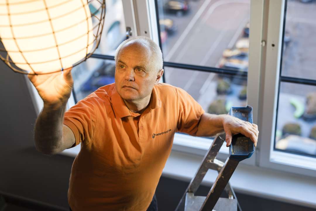 Fastighetsägare byter glödlampa i ett trapphus på en stege